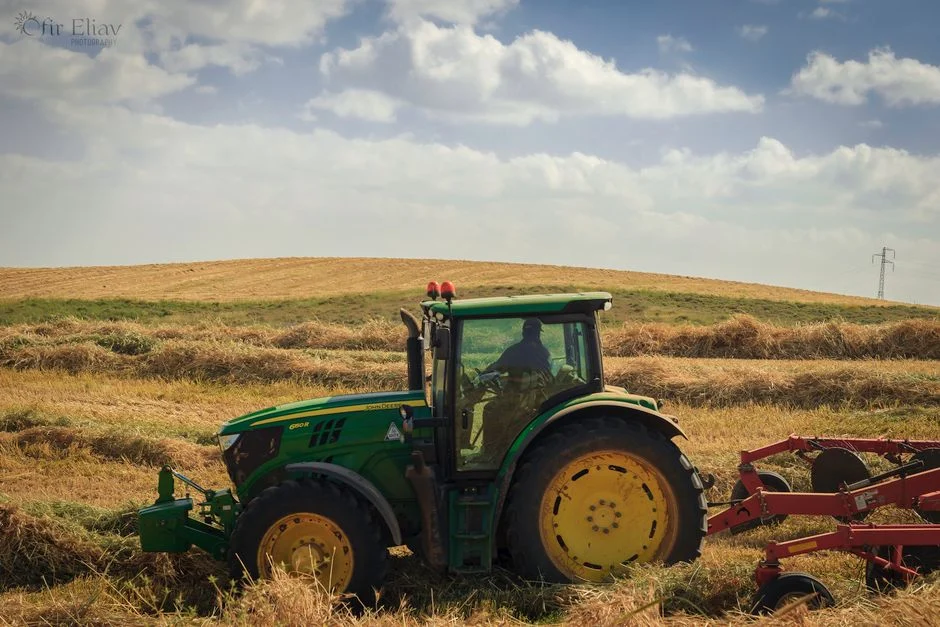 Big Tractor Tires: How Big They Get, What They Fit and Cost A green tractor working in a hay field with blue skies during harvest season