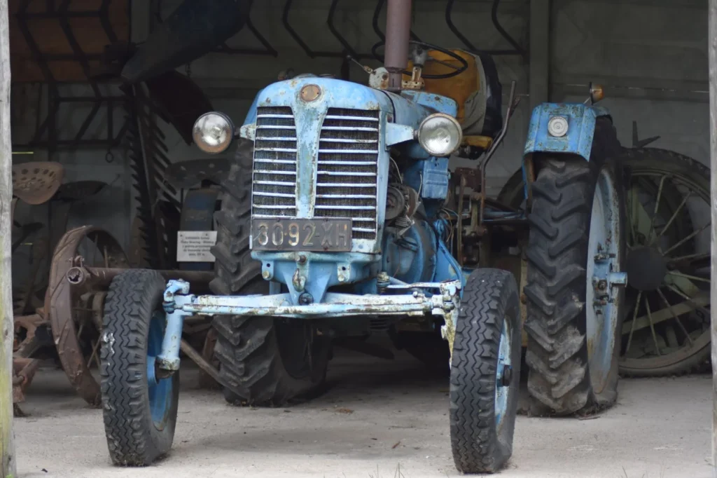 Firestone Tractor Tires: Who Makes Them and Which Line Fits Weathered vintage blue tractor parked inside a rural barn