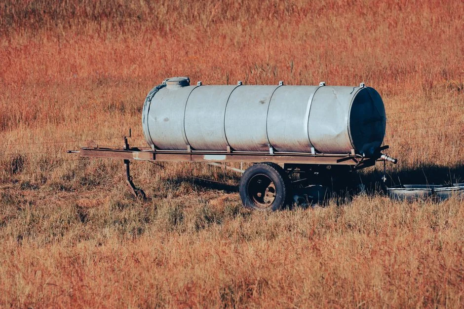 A metal storage tank on wheels set in a dry grassy field, conveying rural simplicity.