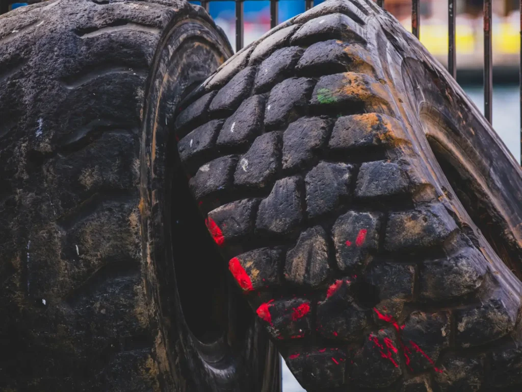 Worn industrial tires stacked outdoors with red paint marks